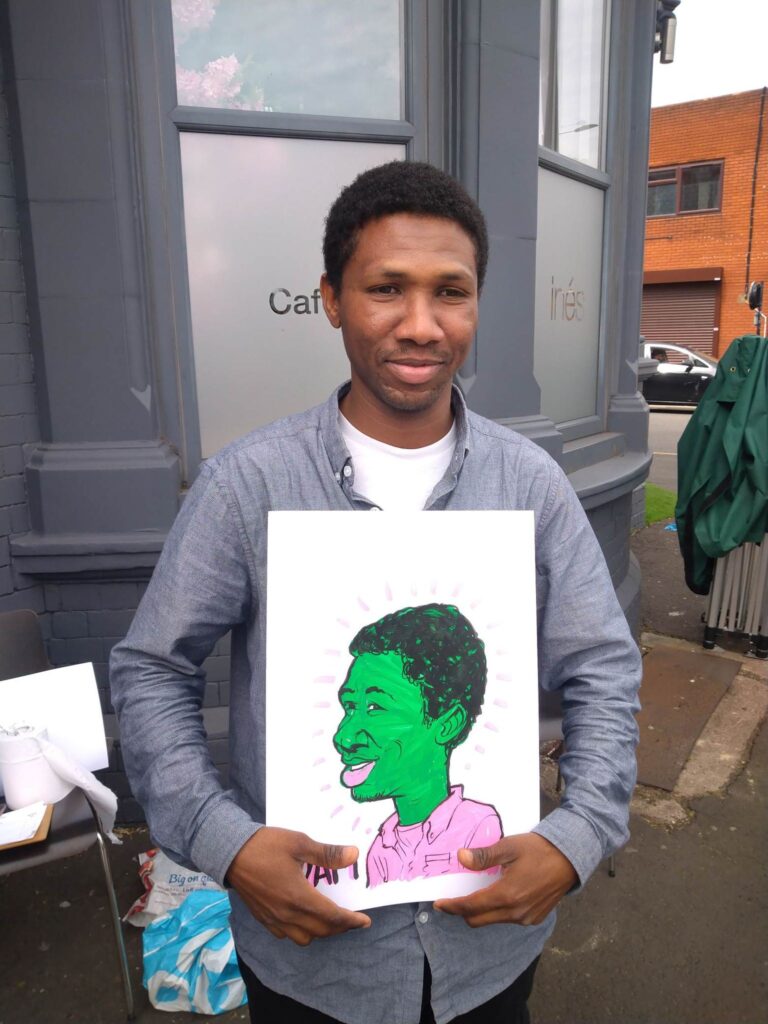 Adam holding up his caricature for the How Were You project for Friction Arts